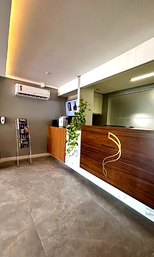 Recepção da Estética Plenure com balcão de madeira, planta e iluminação quente