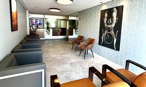 Sala de espera da Estética Plenure com poltronas cinzas e cadeiras de couro conhaque